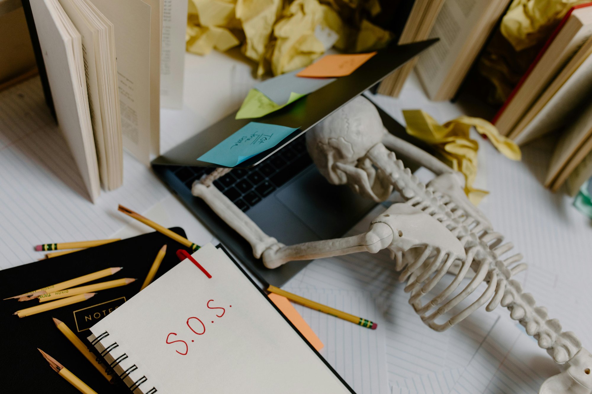Skelet achter laptop met S.O.S. briefje